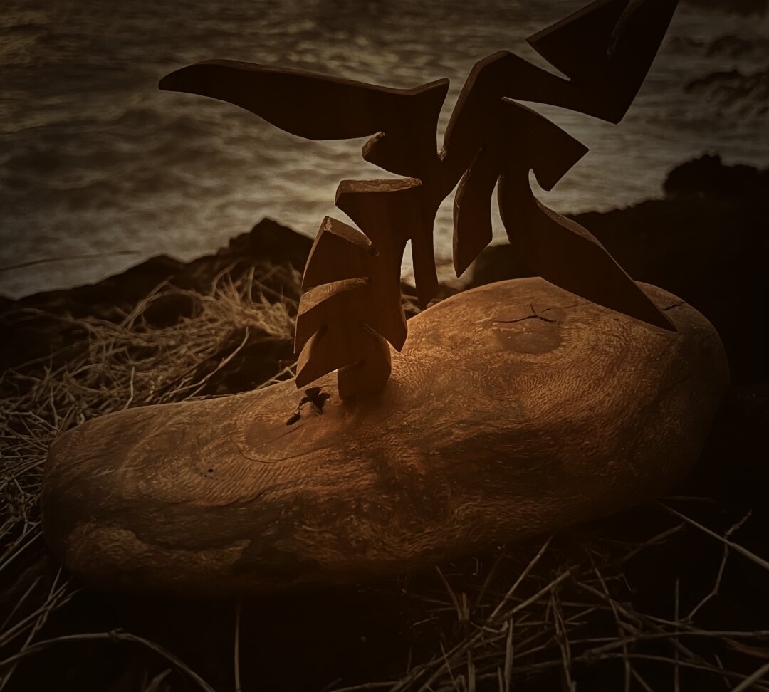 Baleine sculptée sur socle en bois flotté, face à l'océan au coucher du soleil