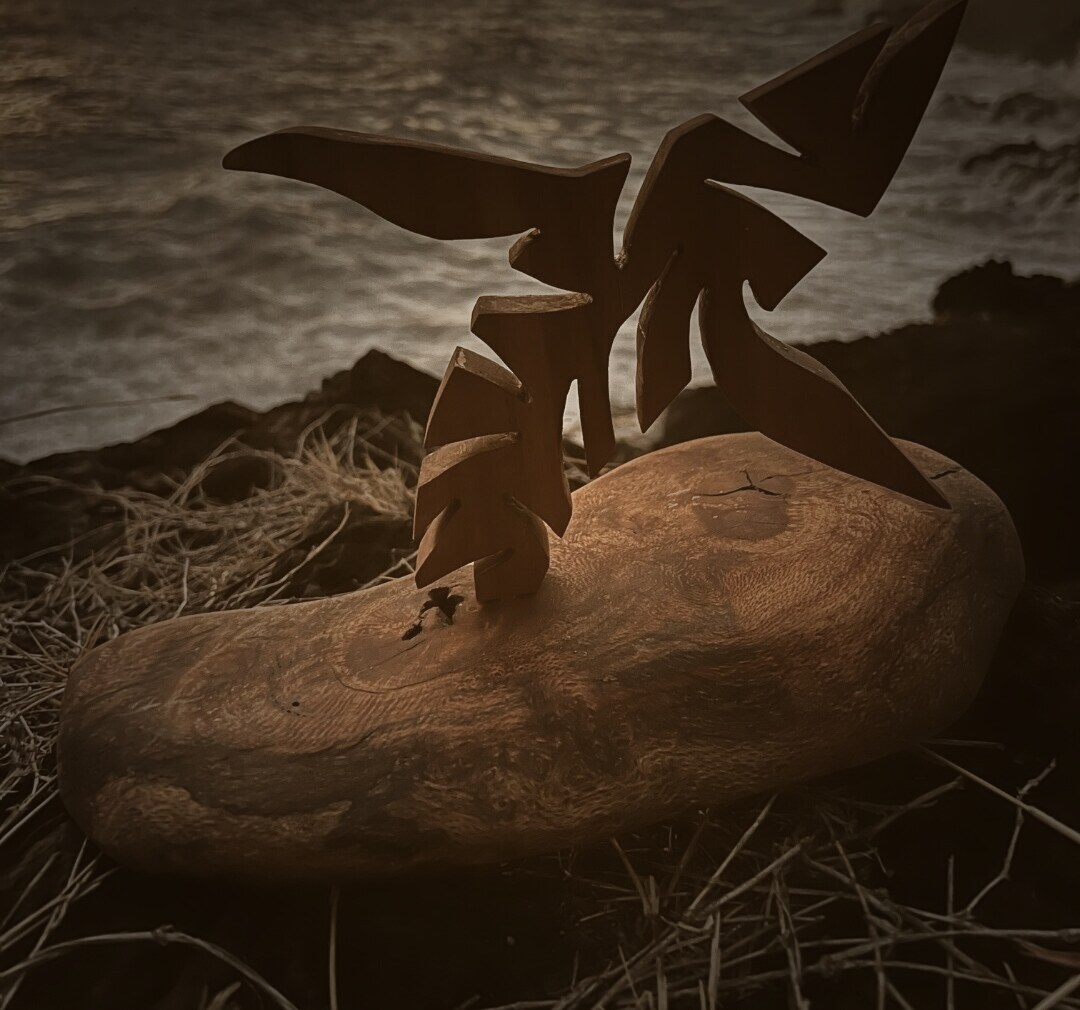 Baleine sculptée sur socle en bois flotté, face à l'océan au coucher du soleil